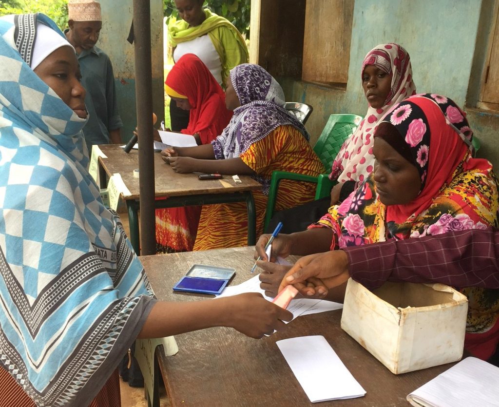En kvinna får pengar från en person som sitter bakom ett bord.