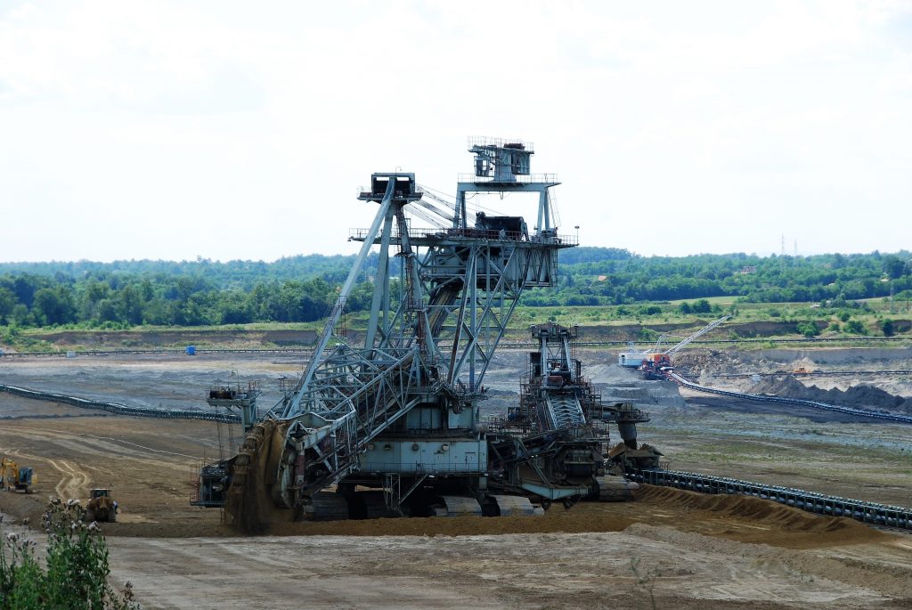 En gruvmaskin står på ett fält. I bakgrunden syns skog och mindre fordon.