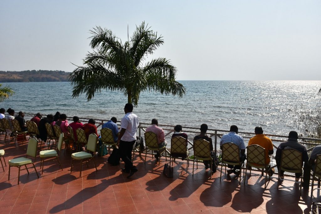 Workshop-deltagare sitter på rad längst med en balkong med utsikt mot havet. De sitter med ryggen mot kameran.