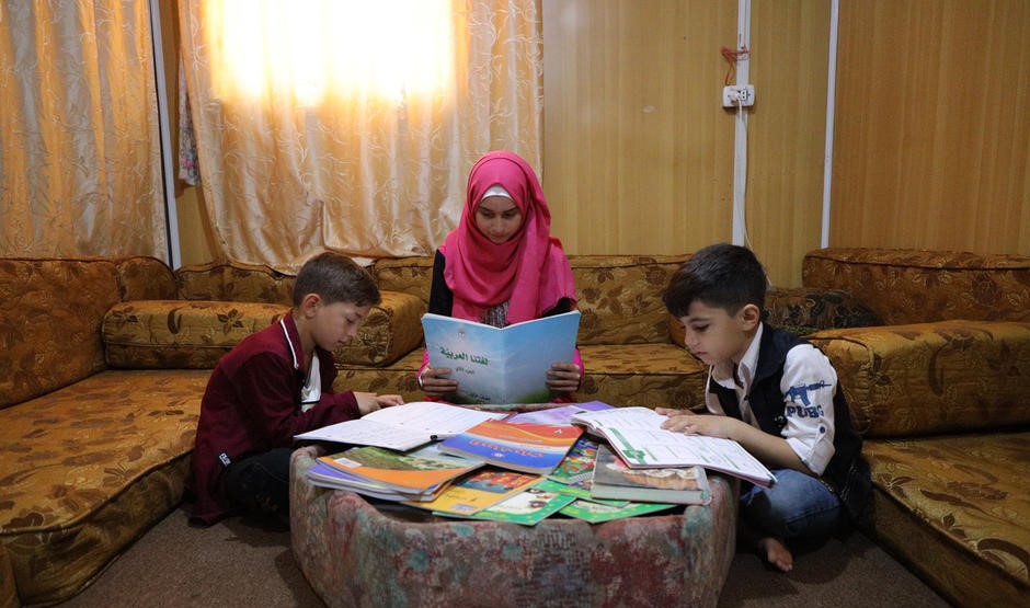 Tre barn sitter på golvet och läser.