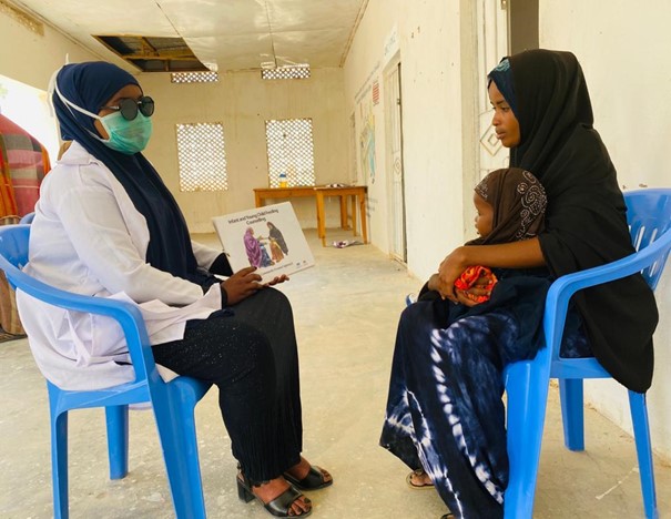 En mamma med sitt barn och en sjuksköterska.