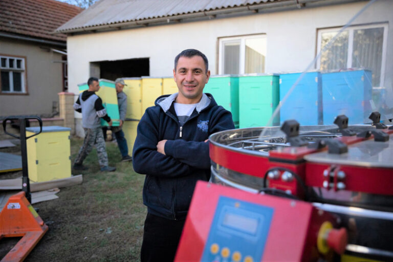 Man står framför bikupor.