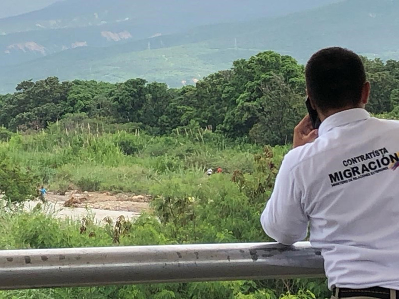 En man står med ryggen mot kameran och ser ut över personer som går i skogen.