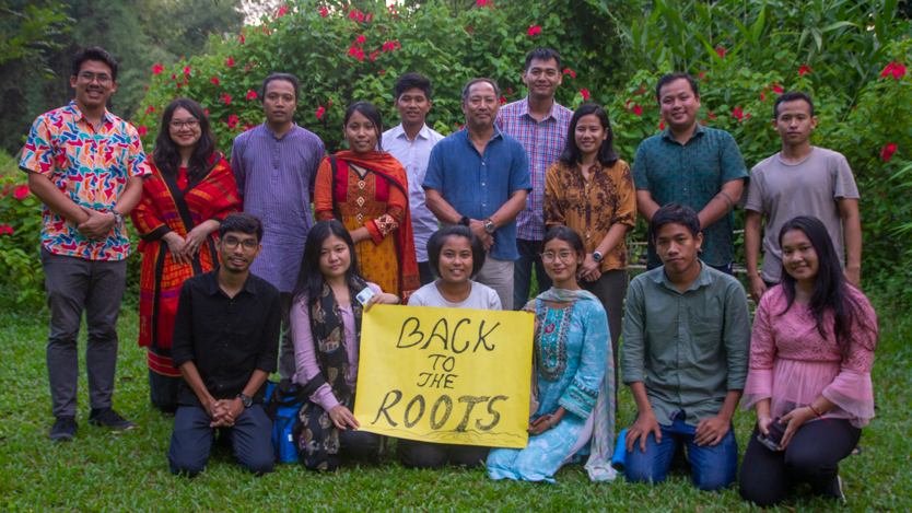 Gruppbild på urfolksungdomar. De håller i en skylt där det står "Back to the roots".