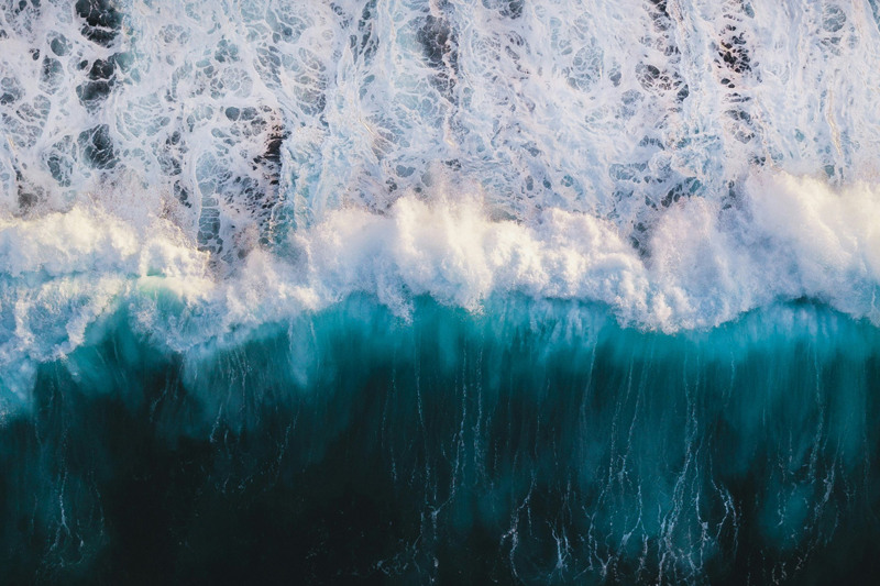 Vågor sedda uppifrån som sköljer upp på en strand.