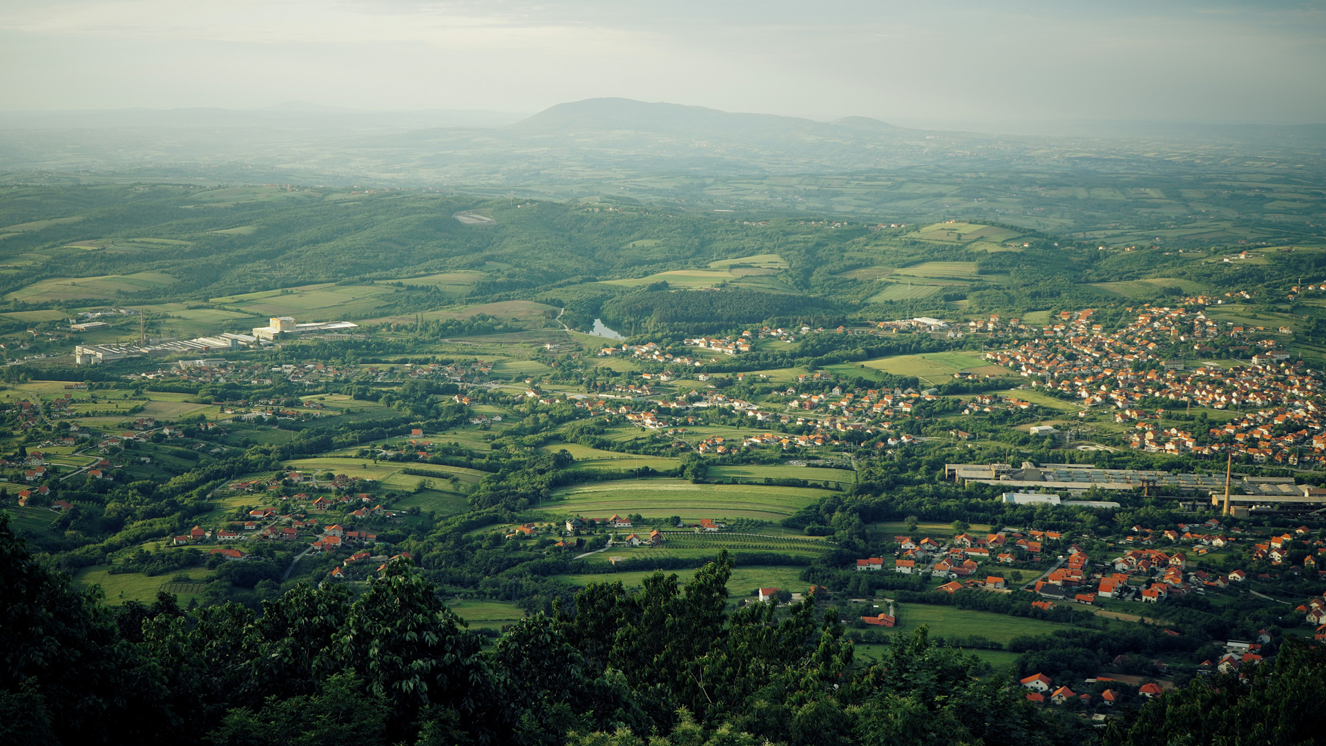 Vy över grönt och böljande landskap med låga vita hus med tegelröda tak.