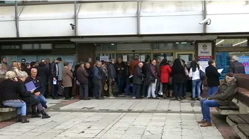 En lång kö ringlar utanför en kontorsbyggnad.