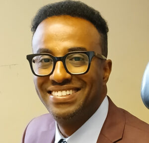 En leende man i glasögon.