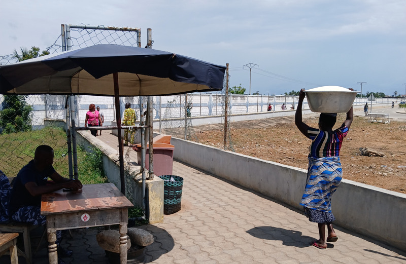En kvinna går o ch bär på ett stort fat med varor som ska säljas.