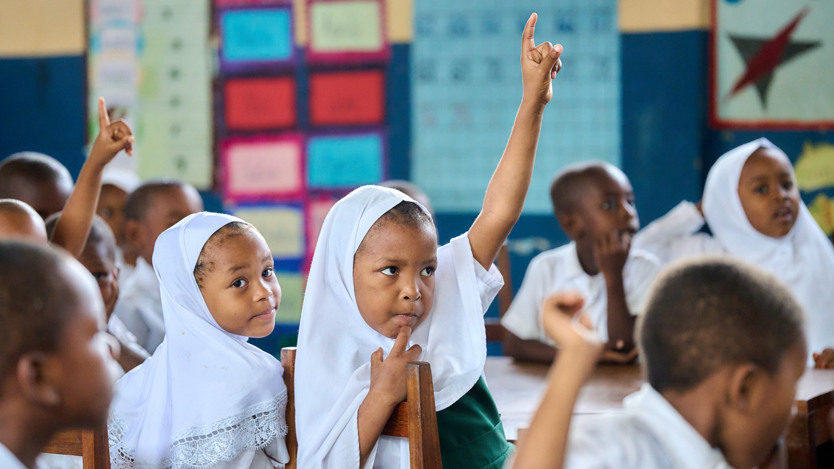 Ett barn räcker upp handen i klassrummet.