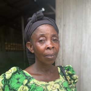 En kvinna står framför en träbyggnad.