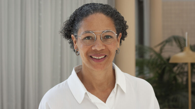 Porträtt på kvinna i kort mörkt hår, glasögon och vit skjorta.