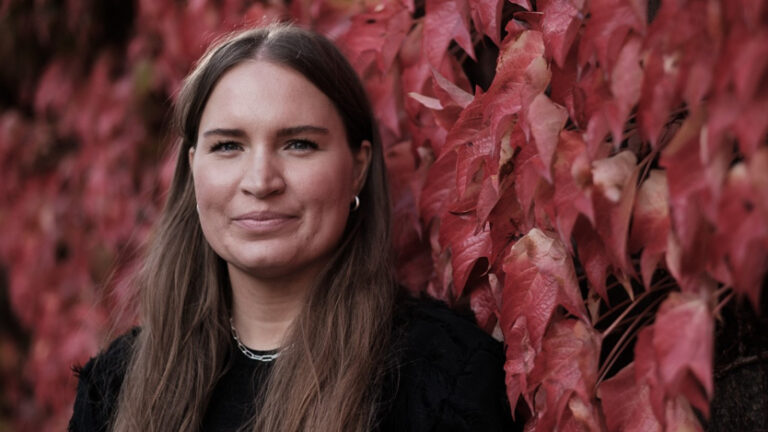 Kvinna med långt brunt hår och svart tröja. 