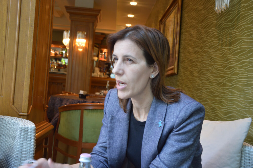 En kvinna i kavaj sitter vid ett bord.