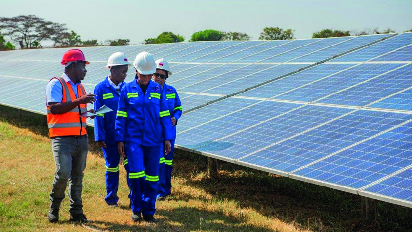 Fyra personer går bredvid en anläggning med solpaneler.