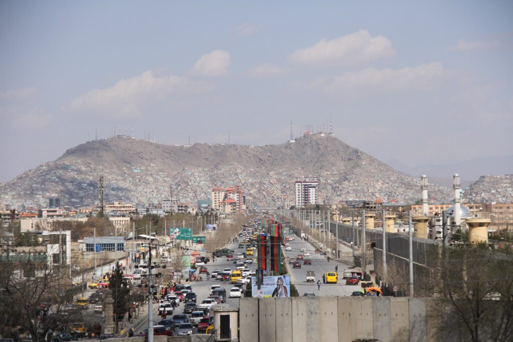 Utsikt över en trafikerad väg i Kabul med berg i bakgrunden.