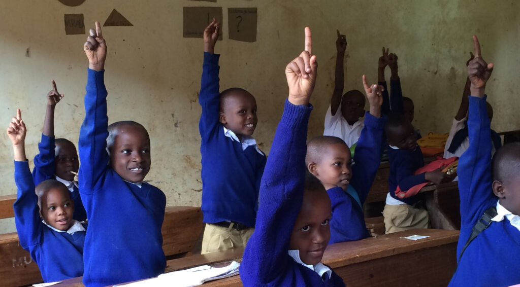 Skolpojkar räcker upp händerna i ett klassrum