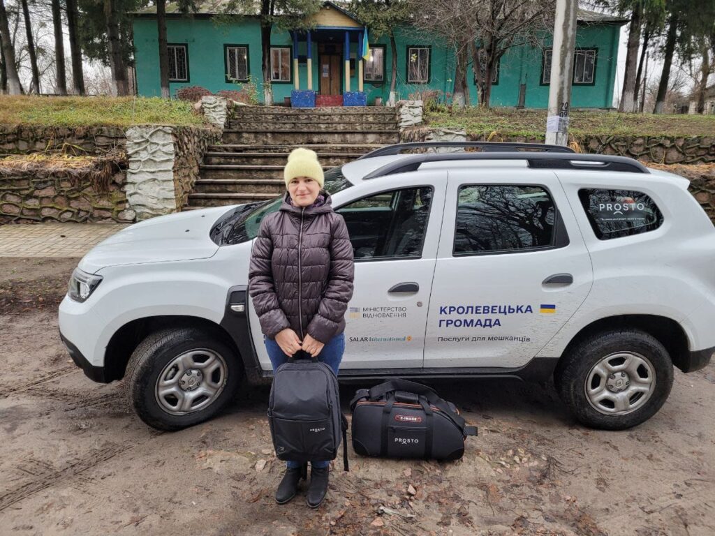 Kvinna står framför kommunens tjänstebil