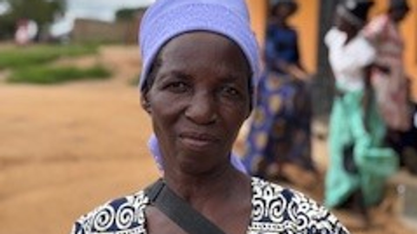 Kvinna poserar i blå huvudduk i Zimbabwe.