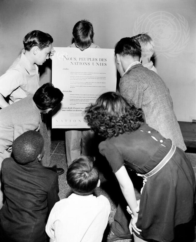 En grupp barn som står runt en skylt.