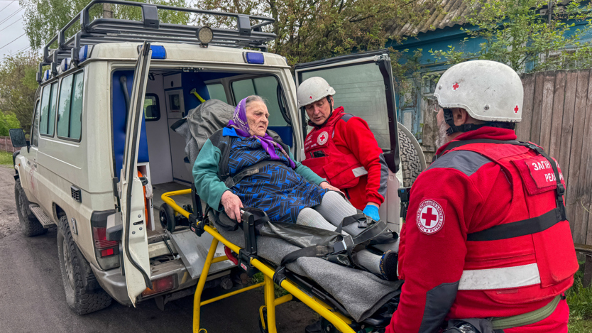 En person på en bår lastas in i en skåpbil.