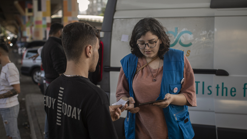 En kvinna med glasögon pratar med en ung man.