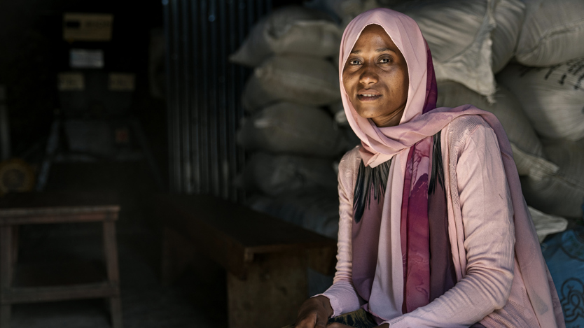 En kvinna med rosa och lila sjal och kläder tittar in i kameran. 