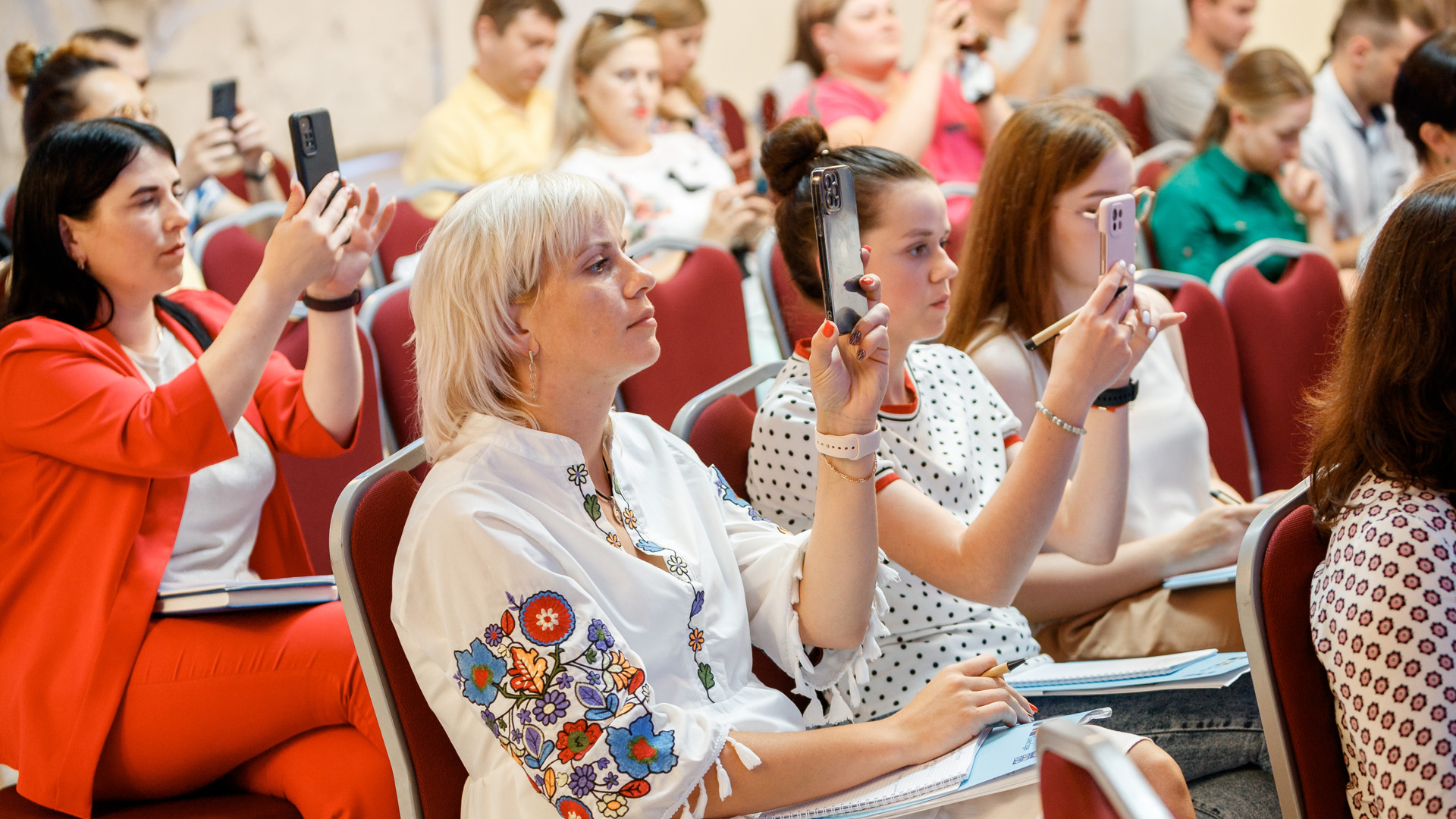 Människor sitter i ett rum och håller upp varsin mobil.