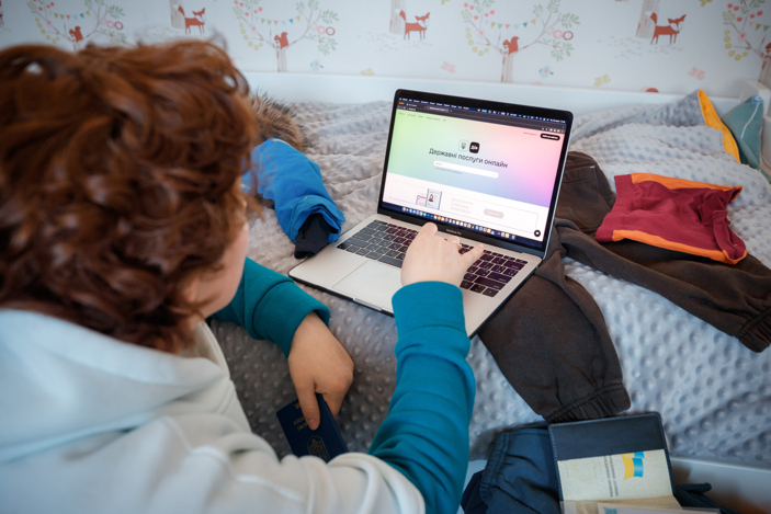 En person syns bakifrån och ligger och surfar på en dator.