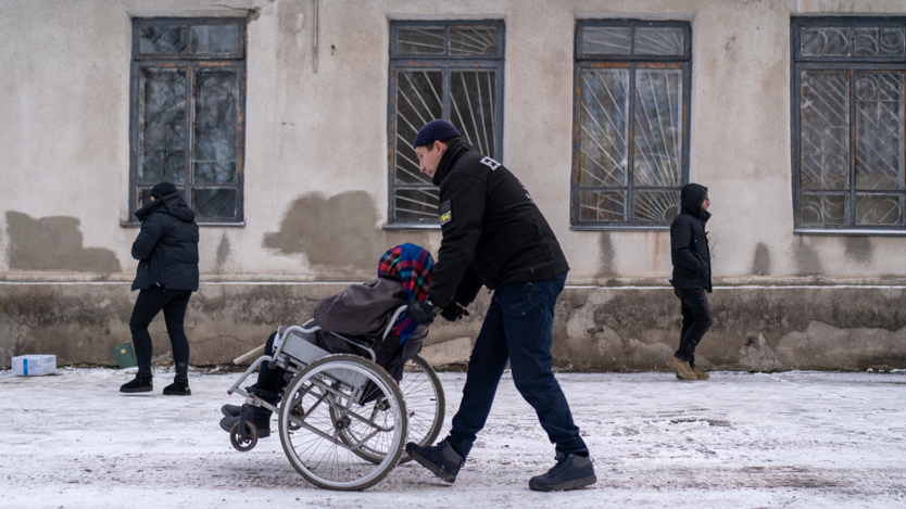 En person kör en person i en rullstol.