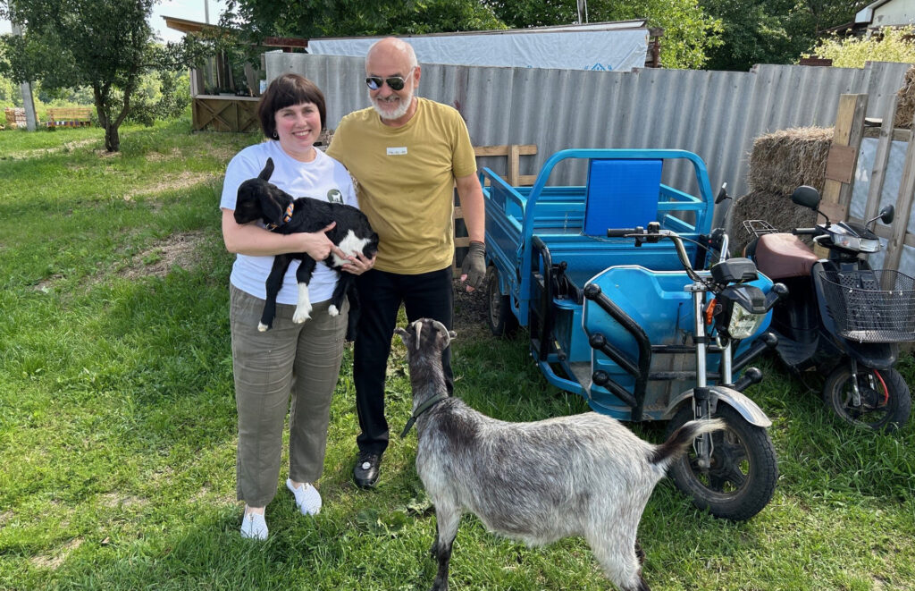 En man och en kvinna står bredvid en get. Kvinnan har en liten get i famnen.