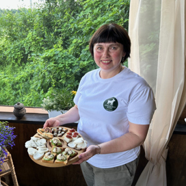 En kvinna håller en tallrik med mat framför ett fönster.