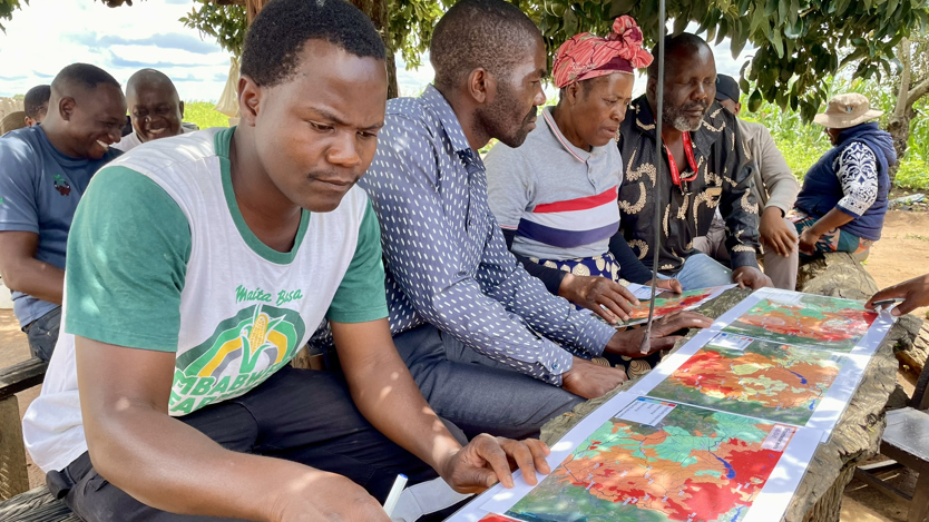 En grupp män som sitter runt ett bord med målningar på.