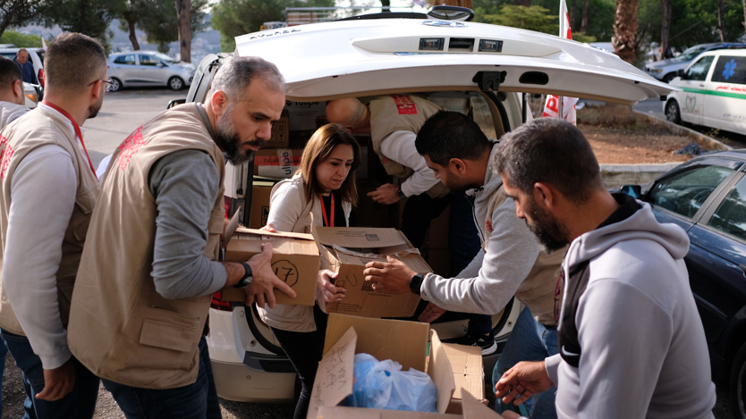 En grupp människor som lastar in lådor i en bil.