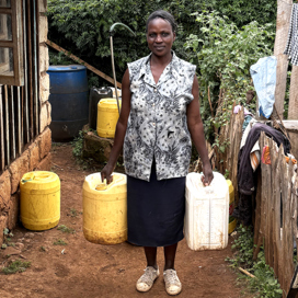 Mary Karuta Mwiti, Ex-Lewa, Kenya. Med vattendunkar vid sitt hus.