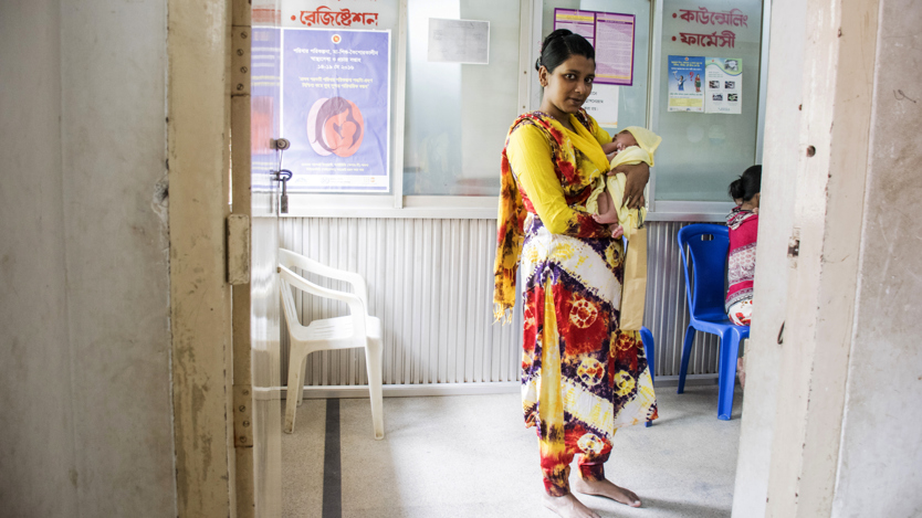 En mamma håller sitt barn i famnen på en klinik i Bangladesh