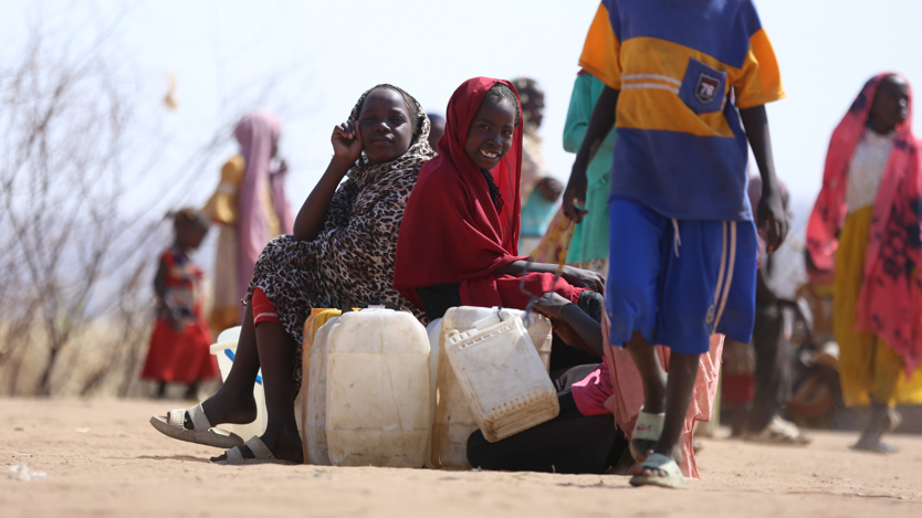 En grupp barn sitter på plastdunkar och säckar.