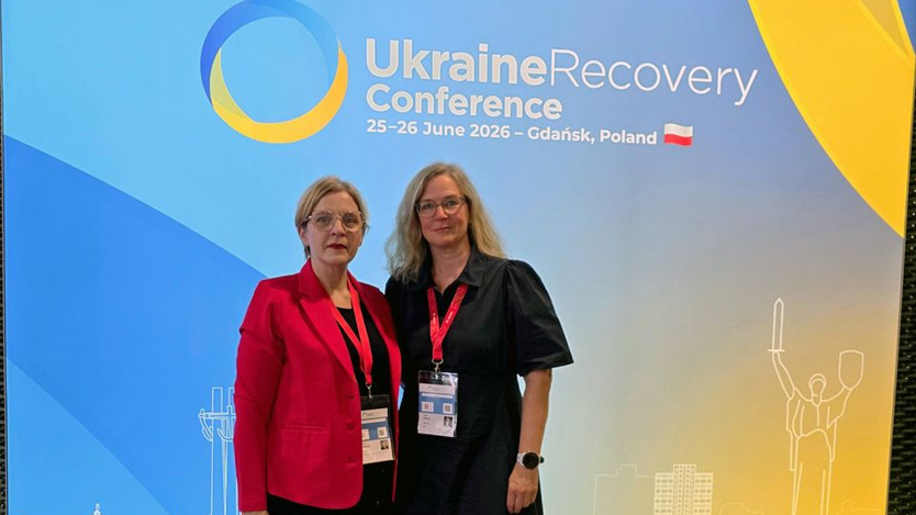 Två kvinnor som står bredvid varandra framför en banderoll där det står Ukraine Recovery Conference