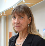 En kvinna i svart jacka står i en byggnad.